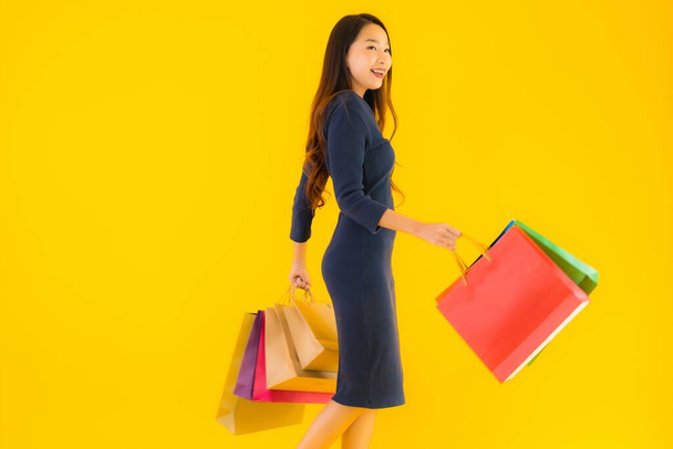 Portrét krásná mladá asijská žena s barevnou nákupní tašku na žlutém izolovaném pozadí - Fotografie, Obrázek