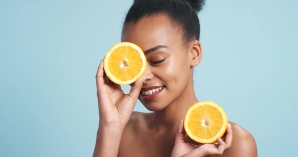 Skincare, lemon and beauty with black woman for youth, wellness and cosmetics against a blue background studio. Dermatology, health and clean face of young female with citrus fruit for cosmetology. - Footage, Video