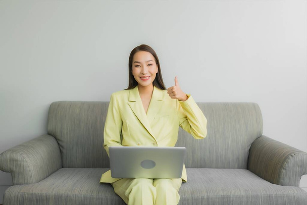 Porträt schöne junge asiatische Frau verwenden Computer-Laptop auf Sofa im Wohnzimmer Interieur - Foto, Bild