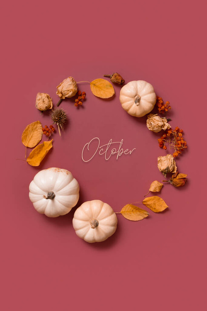 El texto de octubre y la corona plana de otoño de calabaza, hojas y flores con vista a la parte superior de bayas. Formato vertical - Foto, Imagen