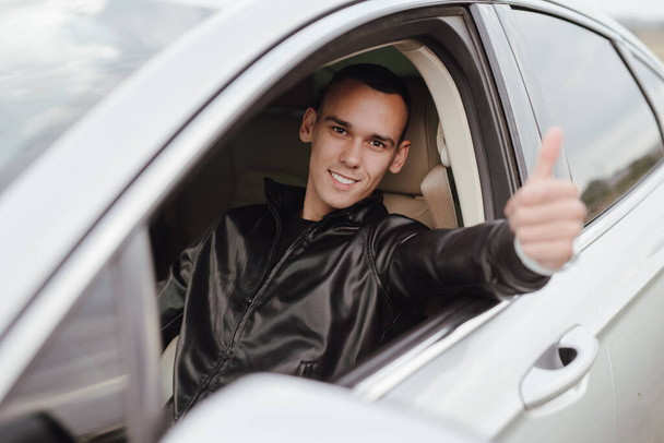 Happy young man driver sitting in his car showing thumbs up finger - Φωτογραφία, εικόνα