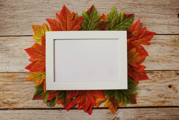 Empty mock up photo frame with maple leaves on wooden background - Foto, imagen