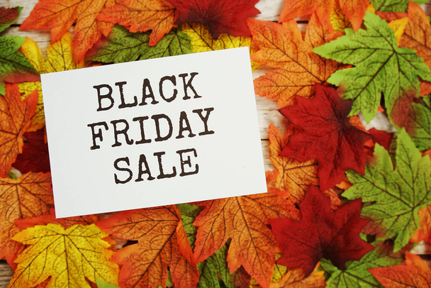 Black Friday Sale text message with maple leaves on wooden background - Fotó, kép