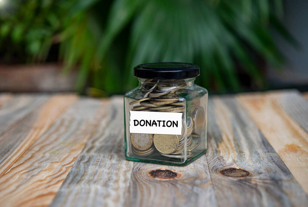 concepto de caja de donación con monedas de oro tarro sobre tabla de madera fondo natural. - Foto, imagen