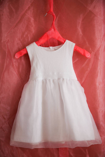 Белый купальник для маленькой девочки на красной вешалке - Фото, изображение