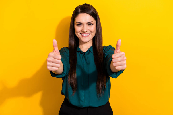 Photo of adorable confident lady dressed green shirt smiling showing two thumbs up isolated yellow color background. - Φωτογραφία, εικόνα