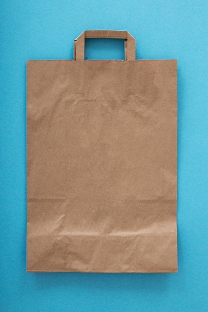 Saco de papel dobrado com uma alça em um fundo azul. Layout para publicidade Foto de alta qualidade - Foto, Imagem