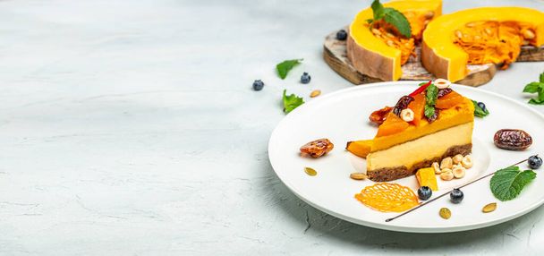 pumpkin cheesecake, slices of pumpkin cheesecake with nuts on a light background. Long banner format. top view. - Photo, Image