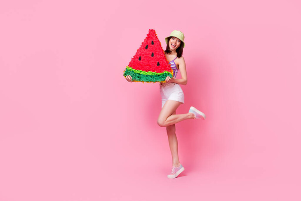 Full length photo portrait of shiny young woman holding big watermelon pinata dressed trendy singlet cap isolated on pink color background. - Fotó, kép
