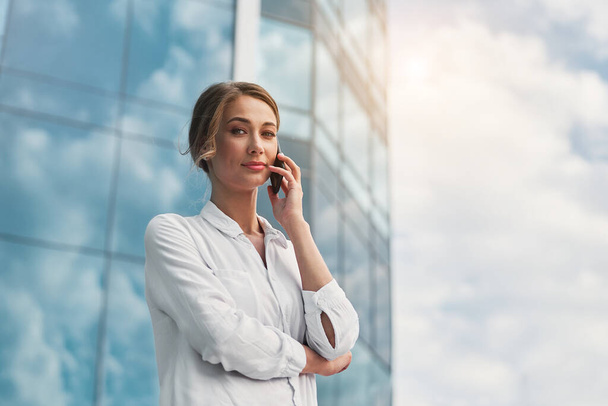 Businesswoman successful woman business person standing outdoor corporate building exterior cell phone Pensive elegance cute caucasian professional business woman middle age dreaming with mobile phone - Foto, Imagem