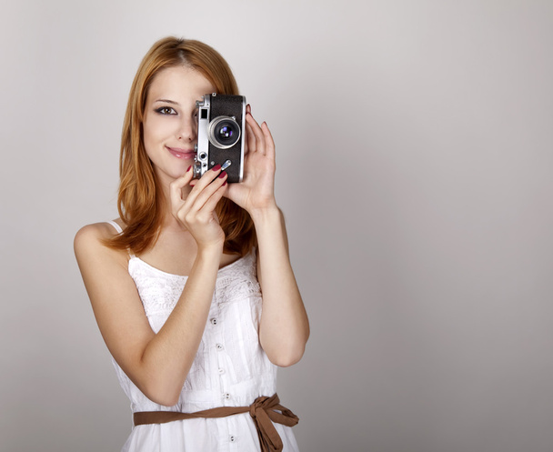 κοκκινομάλλα κοπέλα σε λευκό φόρεμα με το εκλεκτής ποιότητας φωτογραφική μηχανή. - Φωτογραφία, εικόνα
