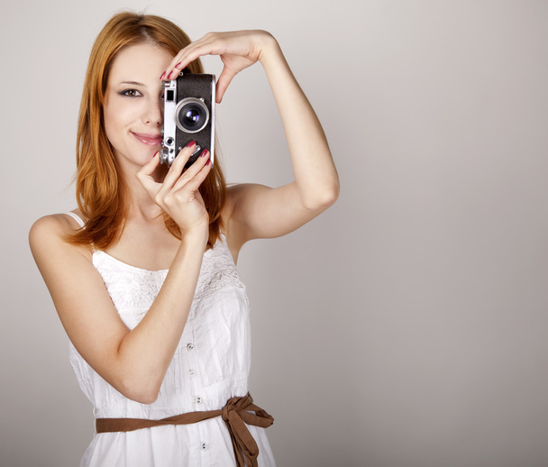 κοκκινομάλλα κοπέλα σε λευκό φόρεμα με το εκλεκτής ποιότητας φωτογραφική μηχανή. - Φωτογραφία, εικόνα