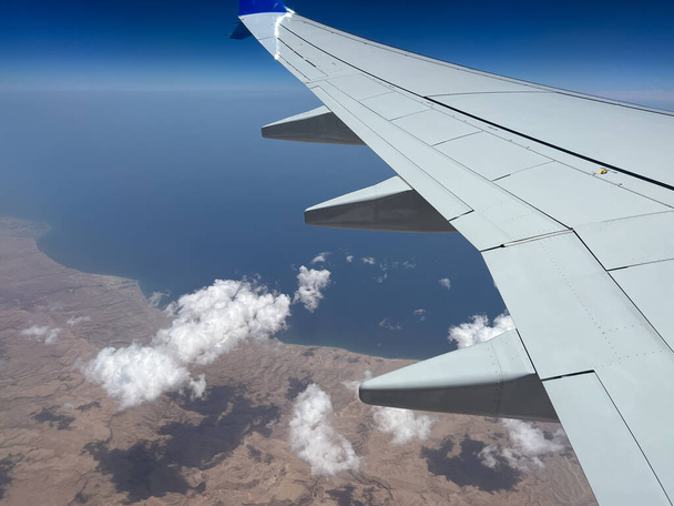 Pohled na část křídla letadla a krásné plovoucí mraky, jak je vidět z okna letadla během letu. - Fotografie, Obrázek