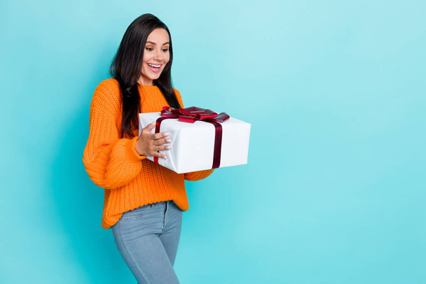 Portrait of nice cute pretty girl long hairstyle wear orange sweater speechless holding giftbox isolated on turquoise color background. - Φωτογραφία, εικόνα