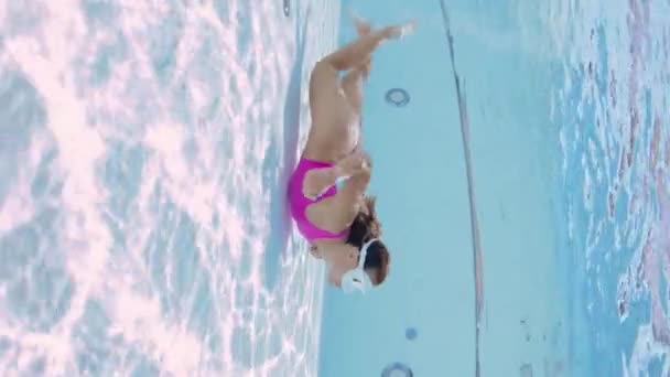 Ελκυστική νεαρή γυναίκα με ροζ μπικίνι κολυμπάει κάτω από την πισίνα - Πλάνα, βίντεο