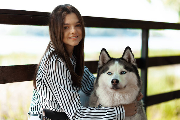 Teenager with a dog in the park caring for a husky. Rest with your pet. - Zdjęcie, obraz