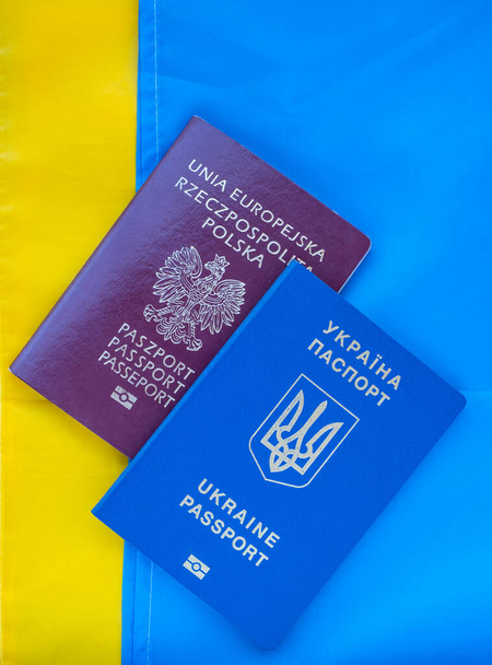 Ukraiński i polski paszport biometryczny na tle flagi narodowej Ukrainy.Międzynarodowy dokument podróży Małżeństwa cudzoziemców.Pomoc Polski dla obywateli ukraińskich.Wsparcie dla Ukrainy - Zdjęcie, obraz