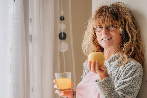 vrouw van middelbare leeftijd thuis ontbijten - Foto, afbeelding