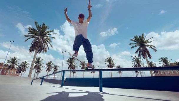 Скейтбордист выполняет трюк в скейт-парке - Фото, изображение
