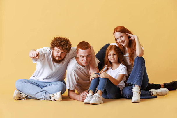Siblings. Friendly family, redhead young men, woman and kid wearing casual style clothes spend time together at studio photo shoot. Look happy. Concept of emotions, love, fashion, relationship - Photo, Image