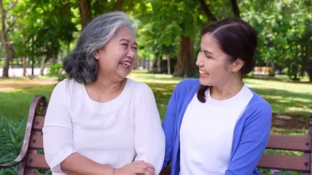 Happy senior mother with gray hair talk and laugh with daughter or caregiver in the park. Concept of happy retirement with care from a caregiver and Savings and senior health insurance, senior care - Footage, Video
