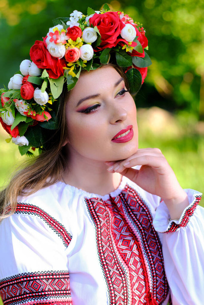 Portret van een mooi meisje met een krans in Oekraïense nationale kleding. - Foto, afbeelding