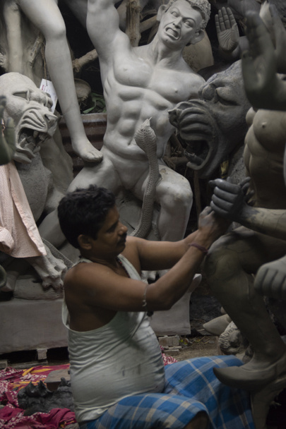 Ein Mann, der Durga-Idol mit selektivem Fokus auf einen bestimmten Teil des Mannes mit Rest des Mannes, das Idol und alles andere verschwimmt. Kalkutta, Westbengalen, Indien - 11.09.2022 - Foto, Bild