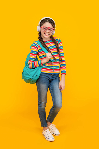 Happy teenage girl listening to music after school yellow background, education. Music education. Non-formal education. - Foto, imagen