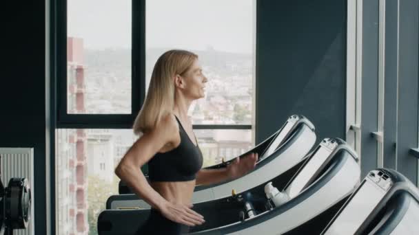 Warm up at gym. Side view shot of active woman athlete running on treadmill, practicing cardio training, slow motion, free space - Footage, Video