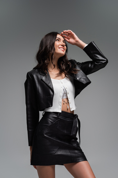happy young woman in leather autumnal outfit smiling isolated on grey - Foto, Imagem