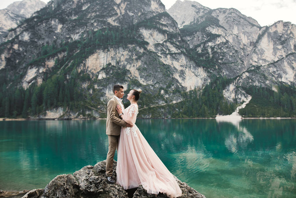 Gorgeous happy couple standing close to each other and looking in eyes near a beautiful lake in the mountains. - Foto, afbeelding