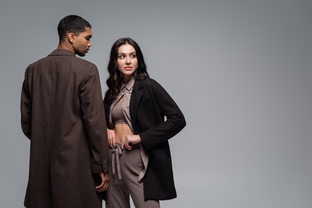 young african american man in woolen coat near stylish woman in black blazer isolated on grey - Photo, Image