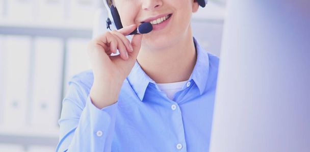 Serious pretty young woman working as support phone operator with headset in office. - Foto, Bild