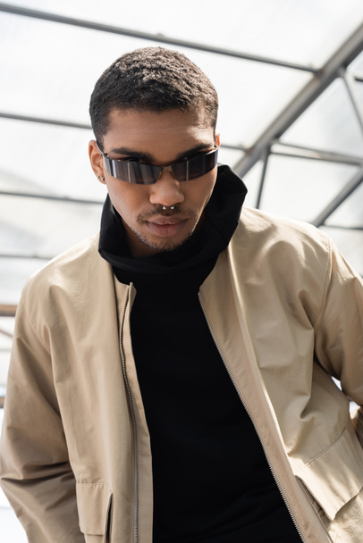 low angle view of young african american in stylish sunglasses standing under roof  - Fotoğraf, Görsel