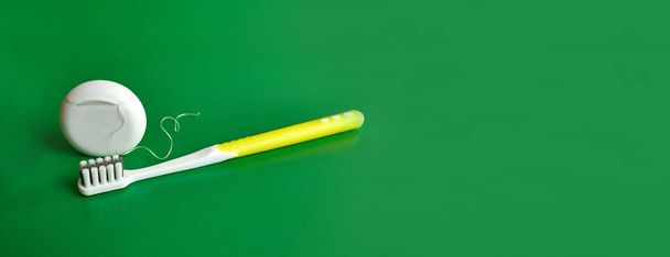 Стоматологічне дзеркало, зубна нитка та зубна щітка на зеленому тлі. Стоматологічна допомога
. - Фото, зображення
