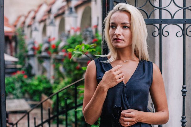 A young, blonde girl in a black blouse and sunglasses poses against the backdrop of an old courtyard in Lviv. Ukraine. High quality photo - Photo, image