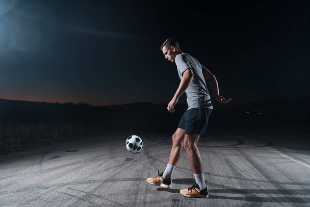 portrait of a young handsome talented soccer player man on a street playing with a football ball. High quality photo - Photo, Image