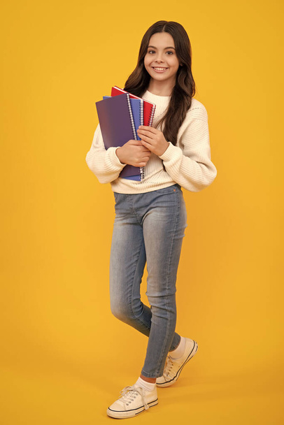 Schoolgirl with copy book posing on isolated background. Literature lesson, grammar school. Intellectual child reader. Happy face, positive and smiling emotions of teenager girl - Photo, image