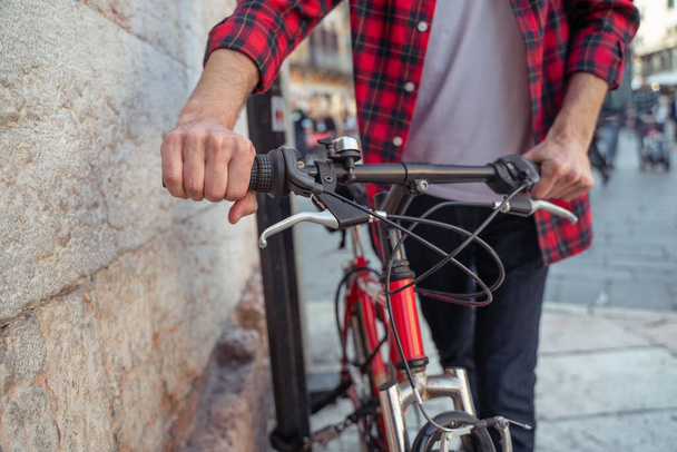 On a bike. Man in plaid shirt with a bike in the street - Photo, Image