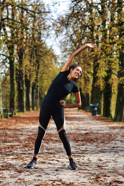 positive middle age woman stretching outdoors preparing for exercise in sportswear - Fotografie, Obrázek