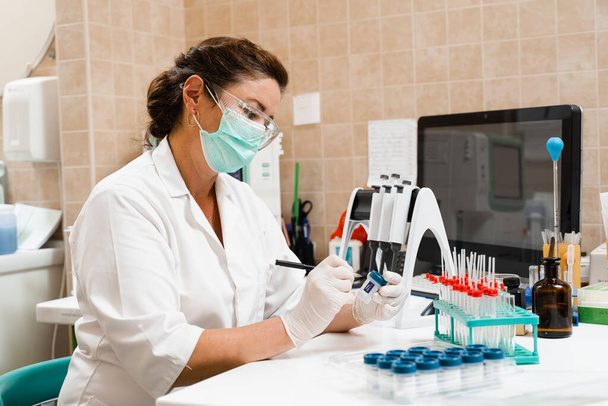 Asistente de laboratorio sostiene tubos de ensayo para el análisis ginecológico y citológico. Mujer científica trabajando en laboratorio médico - Foto, Imagen