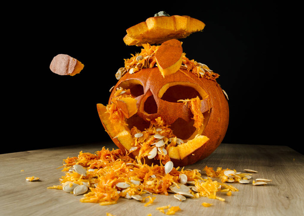 Halloween dýně explodující kusy. Dekorativní Jack-o '-lucerna na dřevěném stole a černém pozadí. - Fotografie, Obrázek