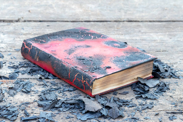 Обугленная книга среди черного пепла с сожжённых страниц - Фото, изображение