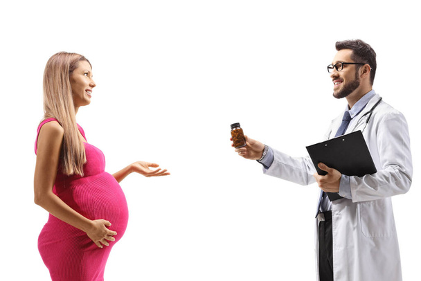 Doctor giving a bottle of pills to a pregnant woman isolated on white background - Foto, Imagen