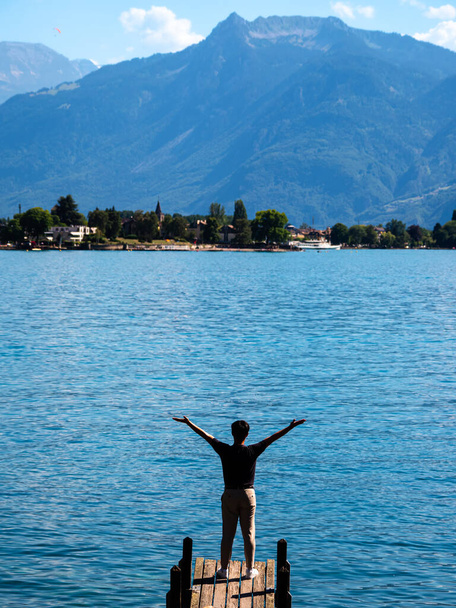 Egy turista kinyújtott karokkal a Genfi-tó mólóján. - Fotó, kép