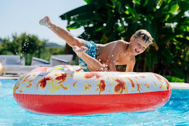 Niño de 8 años de edad, tiene un gran tiempo en un colchón inflable en una piscina en Corfú, Grecia - Foto, imagen