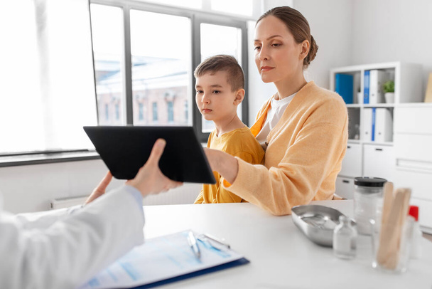 medicine, healthcare and pediatry concept - smiling mother with little son and doctor with tablet pc computer at clinic - Φωτογραφία, εικόνα