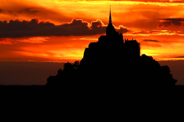 Henkeäsalpaava auringonlasku taivaalla, joka näyttää tulinen ja siluetti saaren Mont Saint Michel Pohjois-Ranskassa Euroopassa - Valokuva, kuva