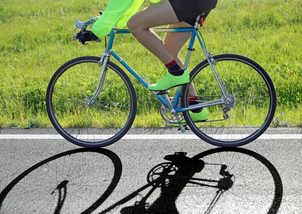 cyklista jede rychle proti světlu s historickou závodní kolo na asfaltové silnici - Fotografie, Obrázek