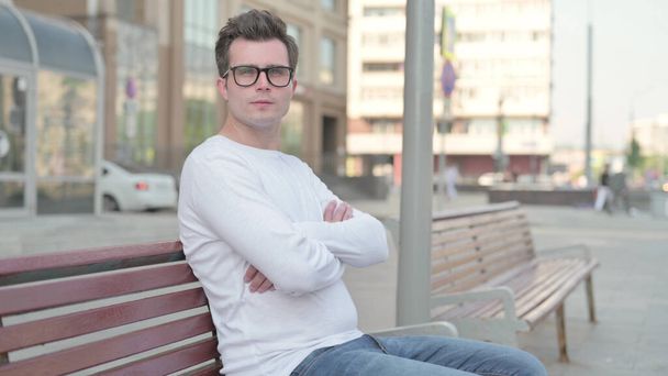 Casual Man Looking at Camera while Sitting on Bench - Zdjęcie, obraz